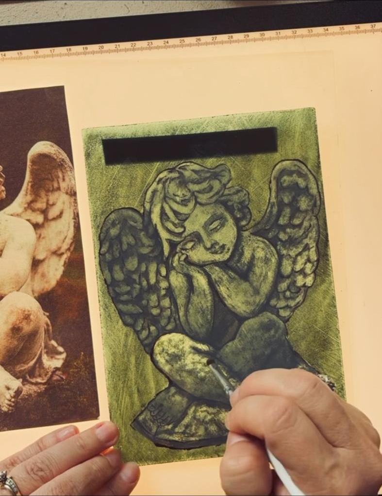 A painted cherub on green glass beside its reference photo