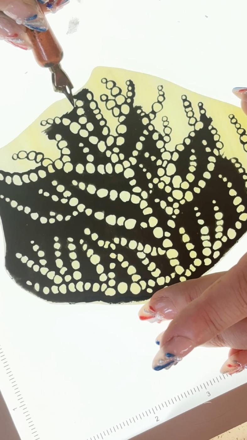 Andrea painting fine detail onto glass with a nib pen